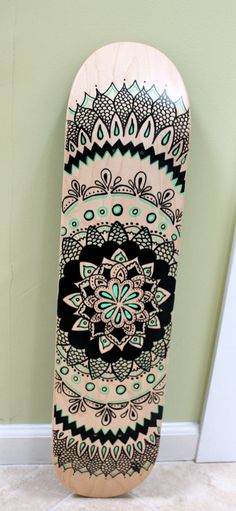 a skateboard with an intricate design on the front and back sides is leaning against a wall