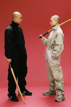 two men standing next to each other holding baseball bats