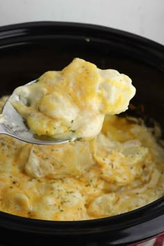 a spoon full of cheese being lifted from the crock pot