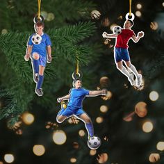 three ornaments depicting soccer players hanging from a christmas tree