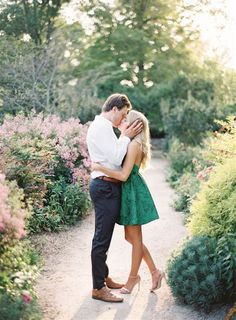 a man and woman embracing each other on a path surrounded by flowers