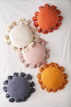 four different colored pillows on a white sheet