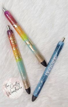 three different colored pens sitting next to each other on a white fur covered surface with the words, the crafty wanderr