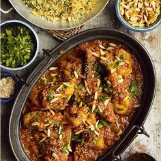 a pan filled with meat covered in sauce and garnished with chopped pine nuts