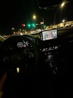 the interior of a car at night with traffic lights and street signs in the background