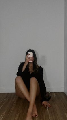 a woman sitting on the floor taking a selfie