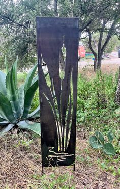 a metal sculpture in the middle of a field with plants growing out of it's sides