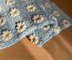 two blue crocheted blankets with white and yellow flowers