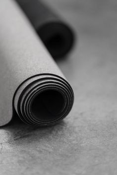 rolled up yoga mat laying on the floor next to it's black and beige cover