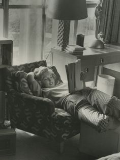 black and white photograph of a person laying on a couch with a book in their lap