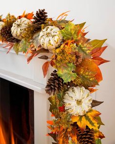 a decorated fireplace mantel with autumn leaves and pumpkins on it, along with pine cones