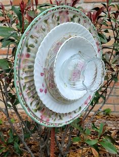 three plates stacked on top of each other in front of a bush and brick wall