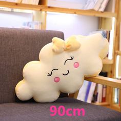 a pillow shaped like a cloud with a bow on its head sitting on a chair