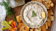 a bowl of dip surrounded by vegetables and crackers