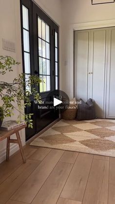 a living room with hardwood floors and white walls, black doors, and a rug on the floor