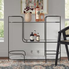 a black chair sitting next to a shelf filled with bottles and liquor on top of a rug