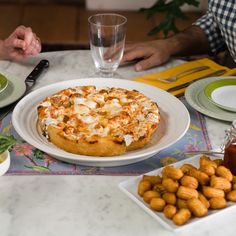 two people sitting at a table with food and drinks in front of them on plates