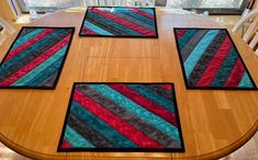 four quilted placemats sitting on top of a wooden table in front of a window