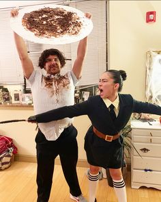 two people dressed as zombies holding up a pie on their shoulders and pulling it out