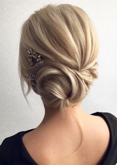 a woman with blonde hair styled into a low updo and some flowers in her hair