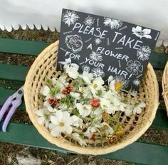 two baskets filled with flowers sitting on top of a green bench next to a sign