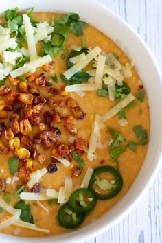 a white bowl filled with soup topped with cheese and green peppers