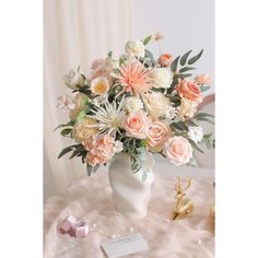 a white vase filled with pink and white flowers on top of a table next to a card