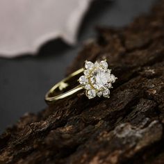 a diamond ring sitting on top of a piece of wood next to a white flower