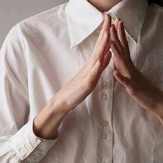 a woman in a white shirt and tie with her hands together