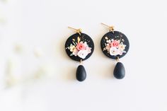 the earrings are decorated with flowers and black stone tears, along with gold - plated hooks