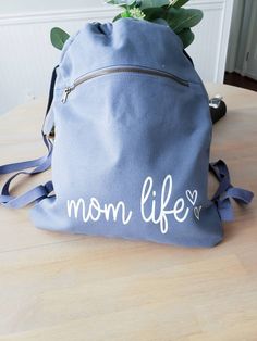 This mom life draw Sting Canvas Bag Is everything! It is Huge and perfect for fitting all your mama aka kids essentials Perfect for running out throwing snacks, wallet and diaper on the go instead of lugging that huge diaper bag around. 17 inches Long 14 1/4 inches wide 14.0 oz., 100% cotton Large main compartment Front zippered pocket with antique brass zipper Webbing straps Available in Black and Blue FOLLOW US ON SOCIAL MEDIA: Instagram: @righthereathome Facebook: @righthereathome Connect wit Cute Everyday Standard Backpack, Cute Cotton Backpack For Everyday Use, Cute Everyday Cotton Backpack, Cute Everyday Diaper Backpack, Backpack With Removable Pouch As Gift, Everyday Backpack With Large Capacity Pouch, Everyday Large Capacity Pouch Backpack, String Backpack, Mom Apparel