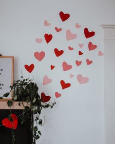 there are many red hearts on the wall next to a potted plant and a framed sign