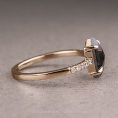 a yellow gold ring with a black and white diamond in the center, on a gray background