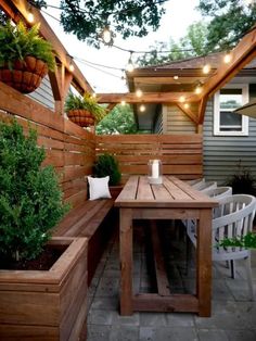 an outdoor table and bench with lights strung over it