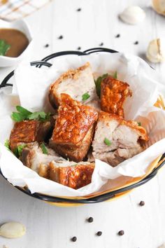 a bowl filled with meat and sauce on top of a white table next to garlic