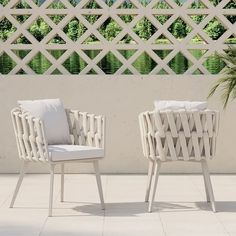 two white chairs sitting next to each other on top of a tile floor near a wall