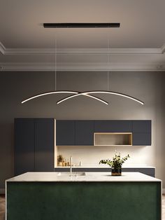 a modern kitchen with an island and green countertops, lights above the sink and cabinets