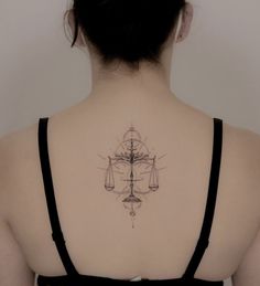 the back of a woman's neck with a tattoo on it that has scales and an hourglass