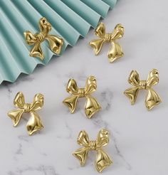 six gold bowknots sitting on top of a marble counter next to a blue fan