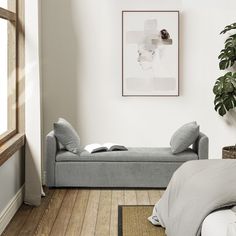 a bed sitting next to a plant in a bedroom on top of a hard wood floor