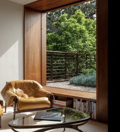 a living room filled with furniture next to a large glass window covered in plants and trees