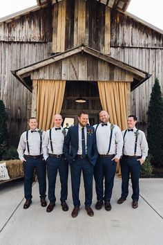 a group of men standing next to each other in front of a wooden structure with curtains