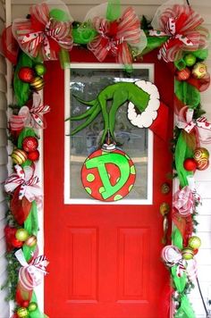 a red door decorated with christmas decorations and an image of a green lizard on top