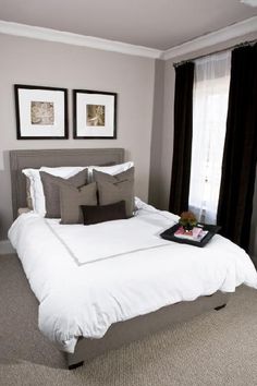 a white bed sitting in a bedroom next to two framed pictures