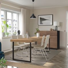 a dining room table with white chairs and a blue couch in front of the window