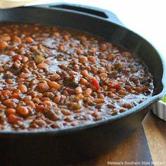 a pot filled with baked beans on top of a wooden table