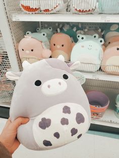 a person holding up a stuffed animal in front of shelves with cupcakes on them