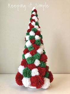 a crocheted christmas tree with red, white and green pom - poms