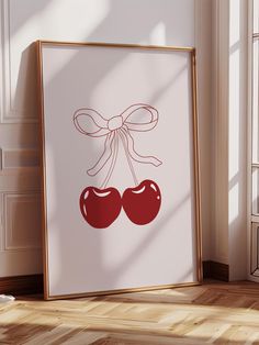 an art print with two cherries tied to it's sides in front of a window