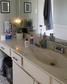 a bathroom with a sink, mirror and other items on the counter top in front of it